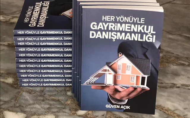 Güven Açık’ın “Her Yönüyle Gayrimenkul Danışmanlığı” kitabı, mermer masada üst üste