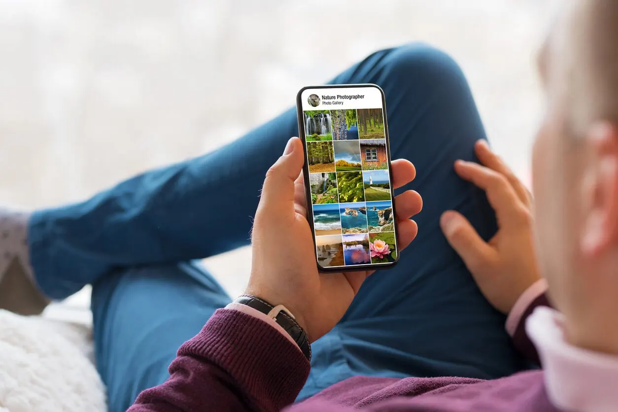 Koltuğa uzanmış bir kişi telefonunda “Nature Photographer” başlıklı fotoğraf galerisine bakıyor